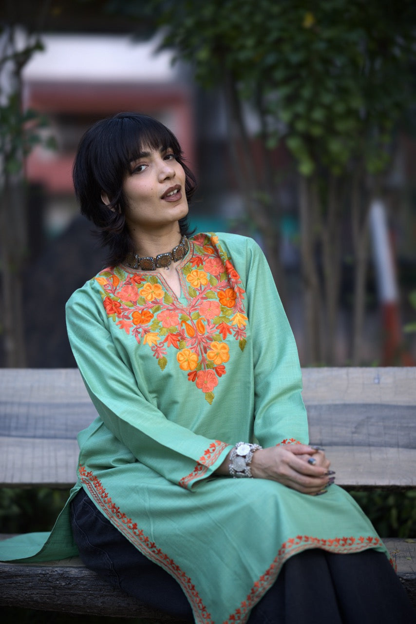 Woman in a green embroidered dress sitting on a bench outdoors