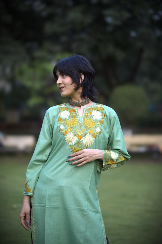 Woman wearing a green embroidered dress in an outdoor setting